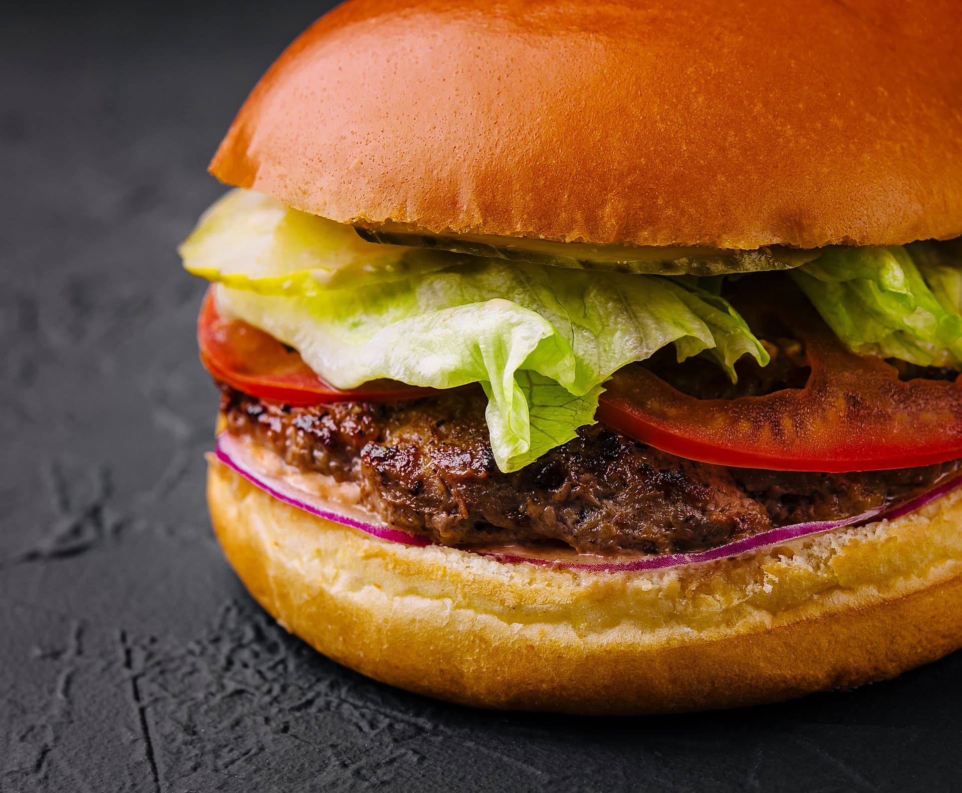 Beef burger in a brioche bun with lettuce, tomato and red onion