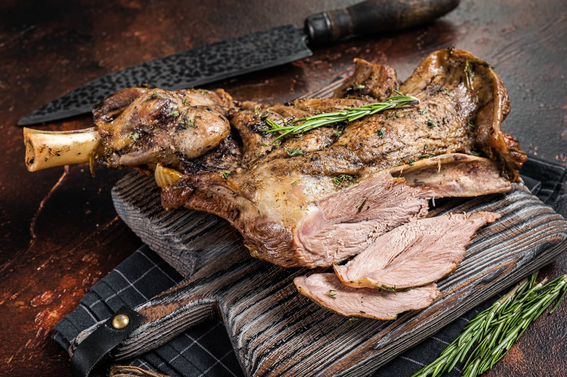 Slow-roasted lamb shoulder with rosemary, carved on a board