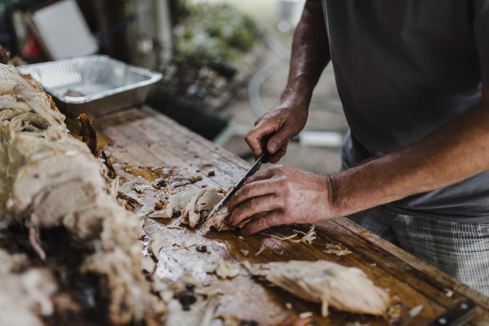 Slow-roasted pork being hand-carved on a wooden board