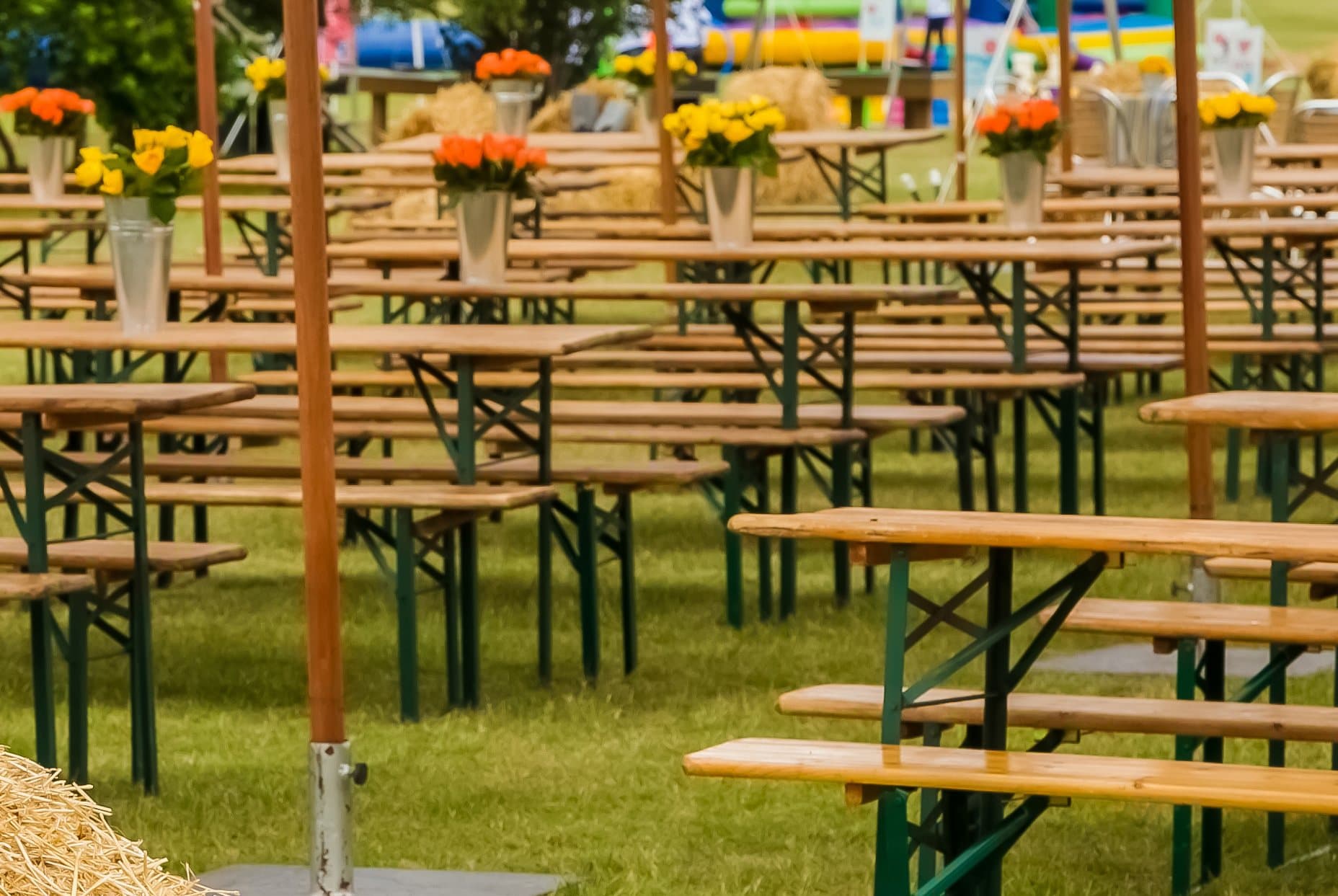 Trestle tables with flowers set out on a field for an outdoor event