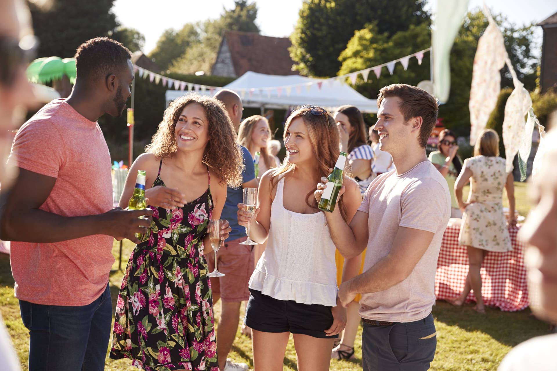 Friends with drinks at a summer garden party with bunting and a marquee