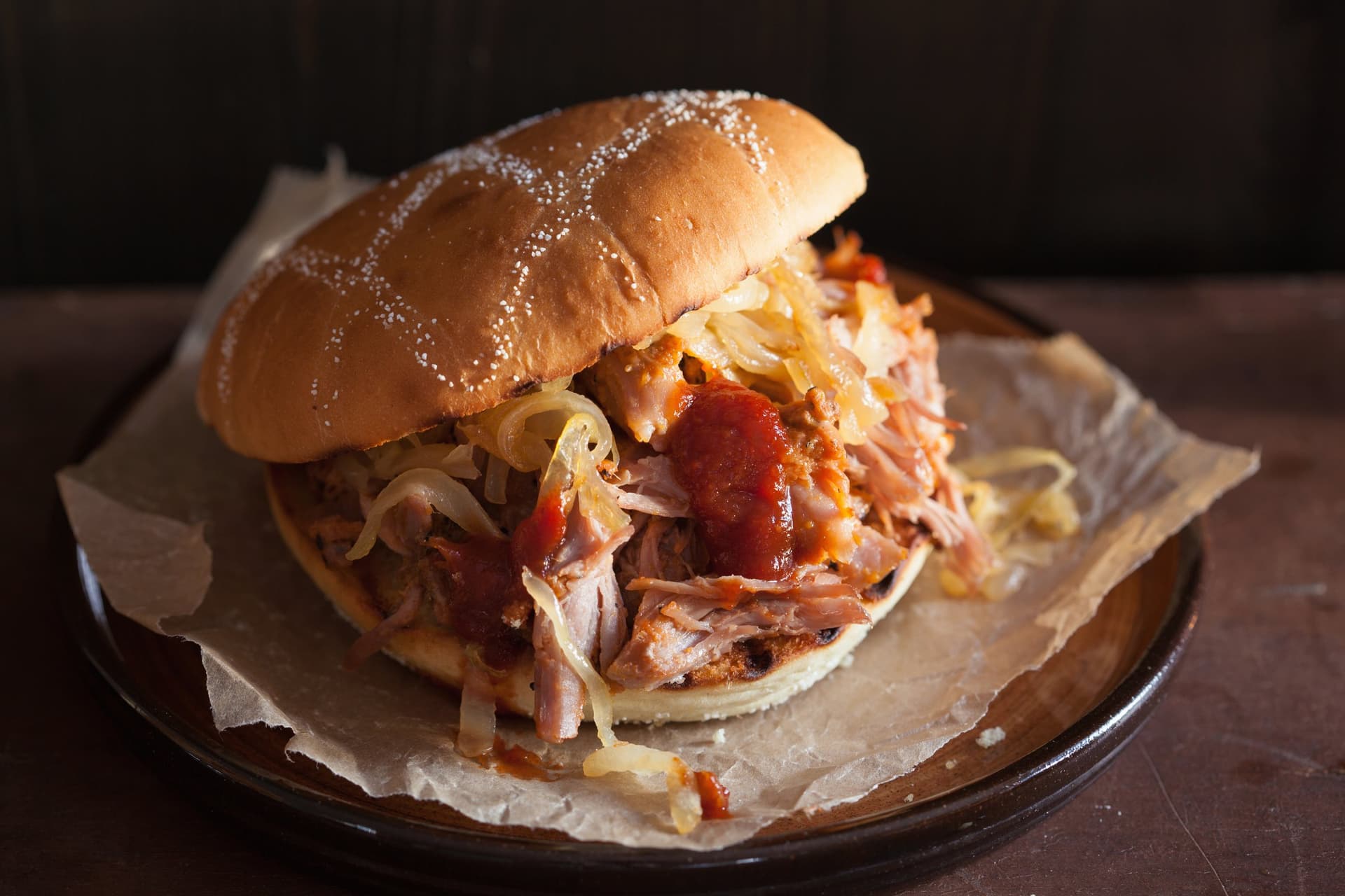Pulled pork roll with sauce and onions on a plate