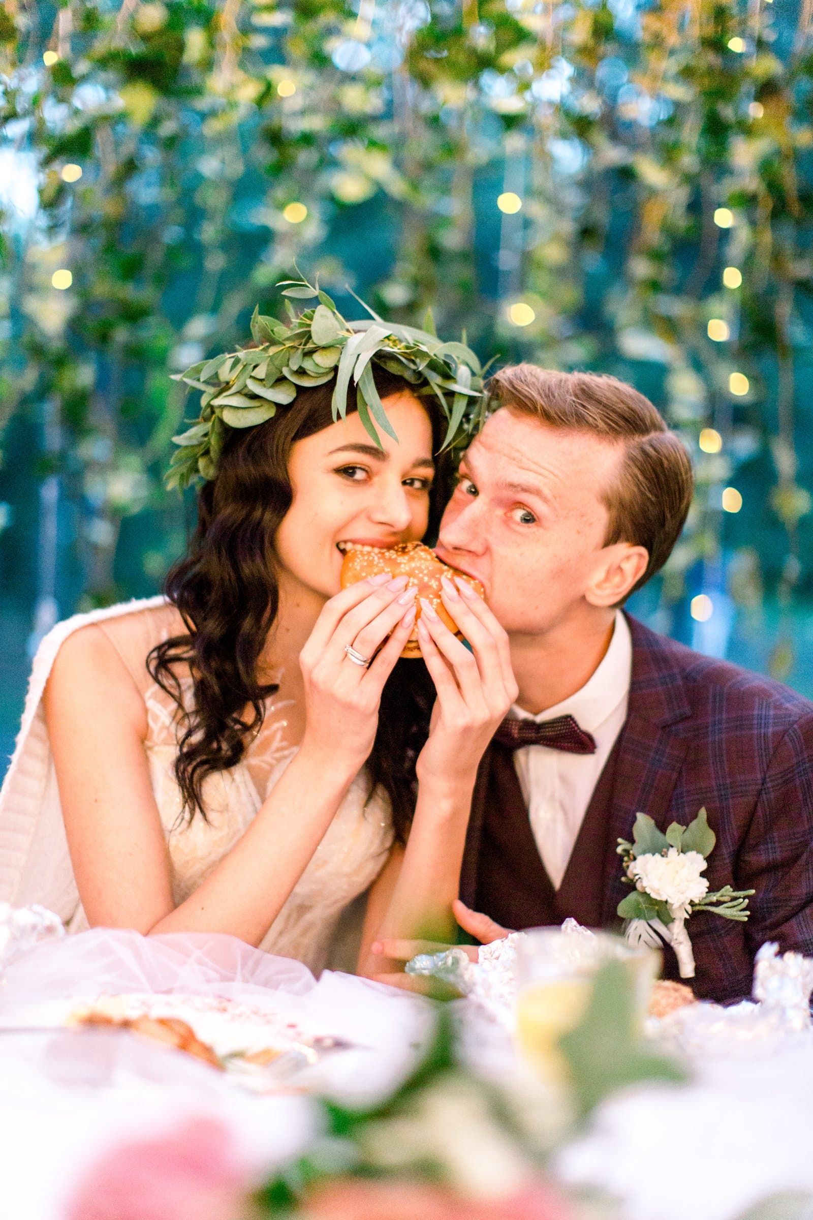 Bride and groom sharing a burger at their wedding reception